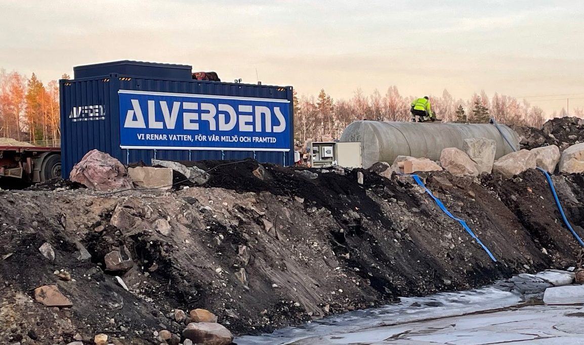 Alverdens blå container vid en arbetsplats med vatten och ljus himmel